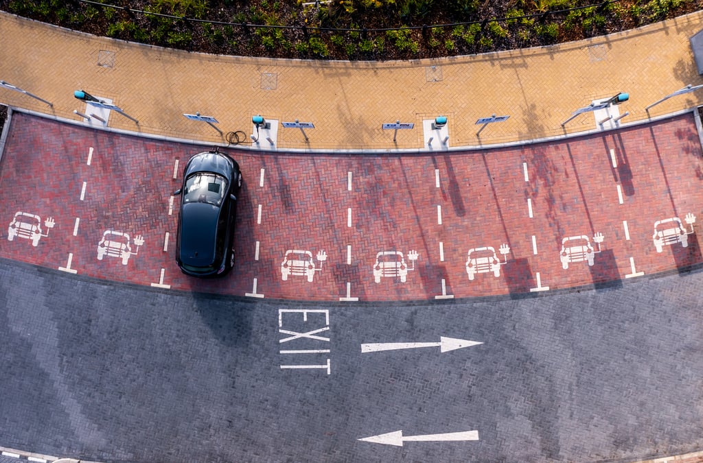 An aerial view of an electric vehicle charging station with an electric car charging in a parking space. Picture: Teamjackson/Adobe Stock