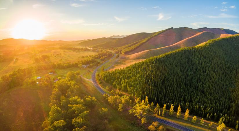 sun shining over green fields and hills