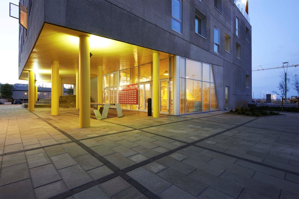 Outside looking at the painted yellow ground floor entrance to the Aarhus Student Housing at dusk.