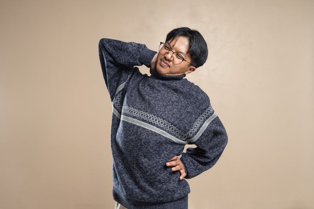 Asian man wearing eyeglasses and sweater stretching indoors, feeling body pain. Picture: Dany Kurniawan/Pexels
