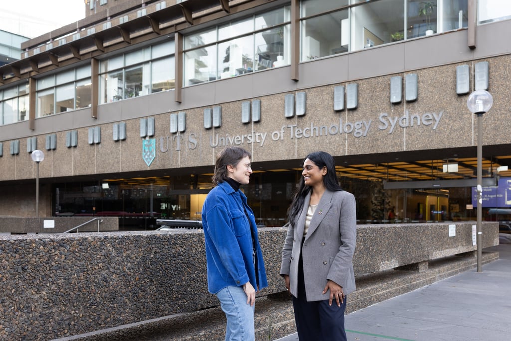 Ash, wearing a grey blazer meeting with Dr Kathryn Greenman, wearing a dark blue denim jacket, outside the main UTS building