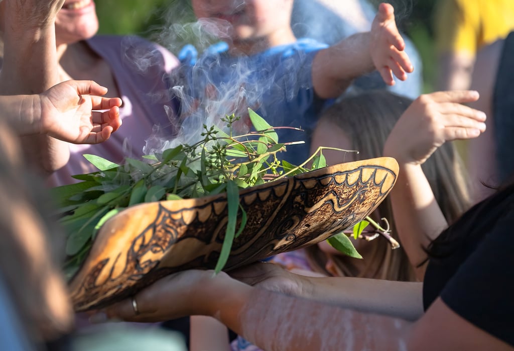 Australian Aboriginal smoking ceremony, human hands are touching the smoke of burning eucalyptus branches. Picture by Elena Pochesneva/Adobe Stock