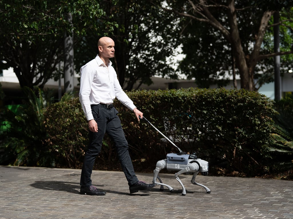 A man walks with a robotic guide through the city campus of University of Technology Sydney.