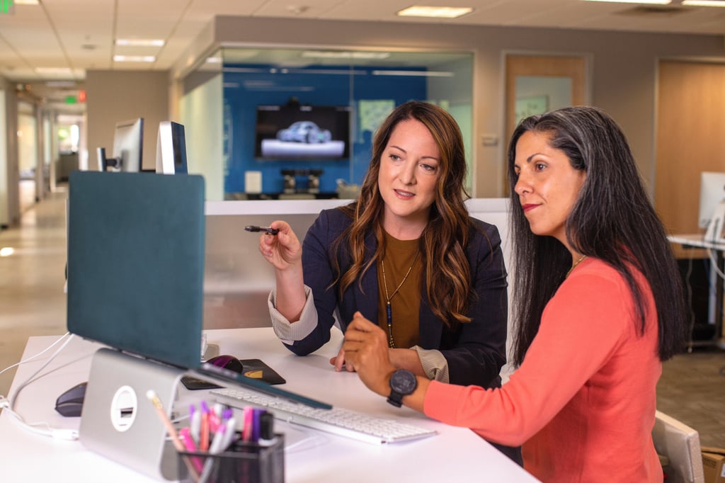 two women looking at a computer screen and discussing what it is displaying