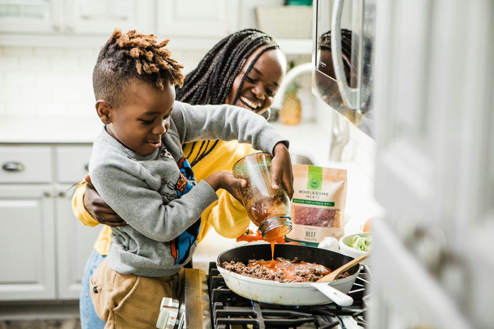 Mum helps child cook a pasta sauce