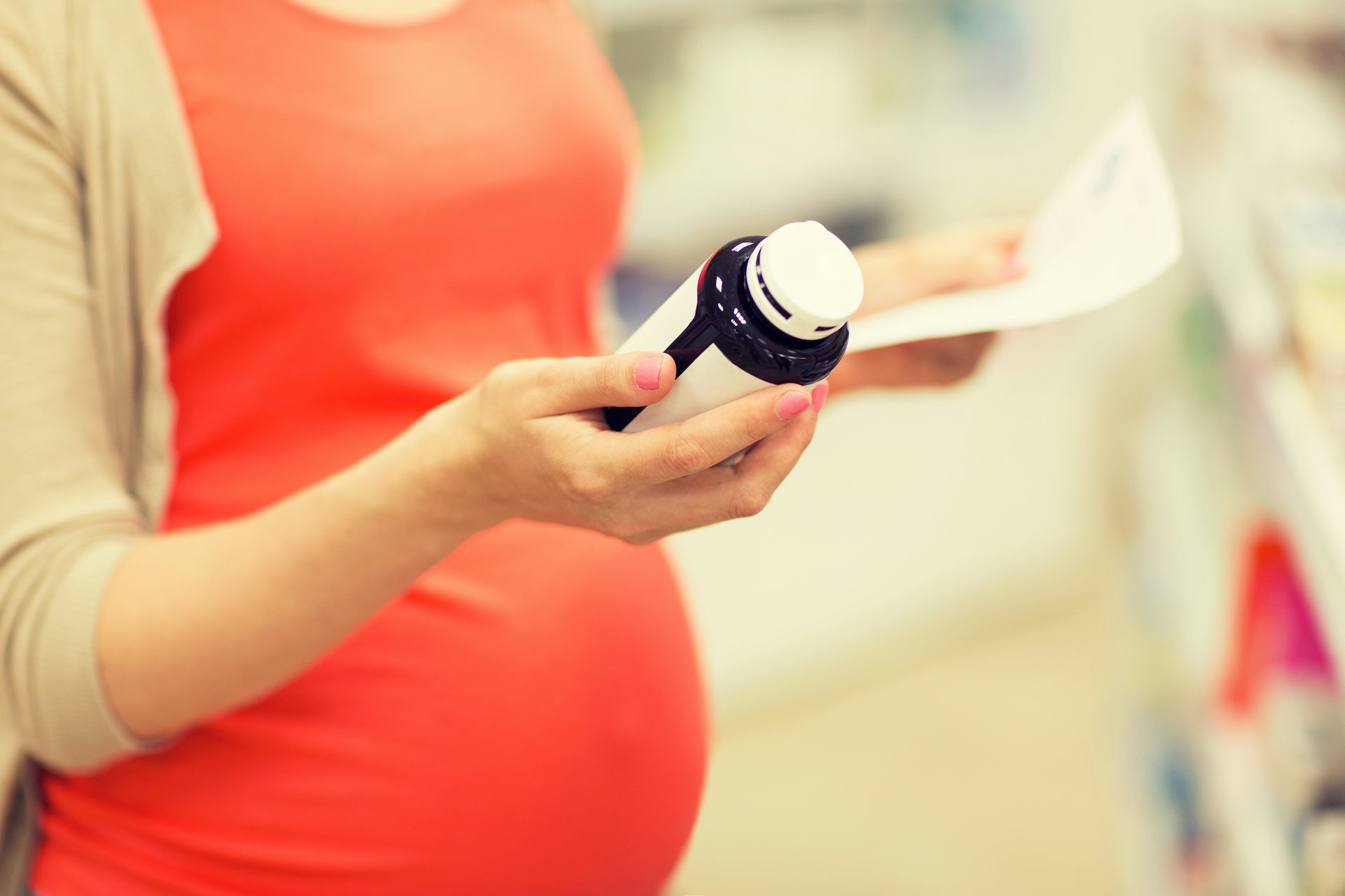 Pregnant person hold pill bottle and information leaflet