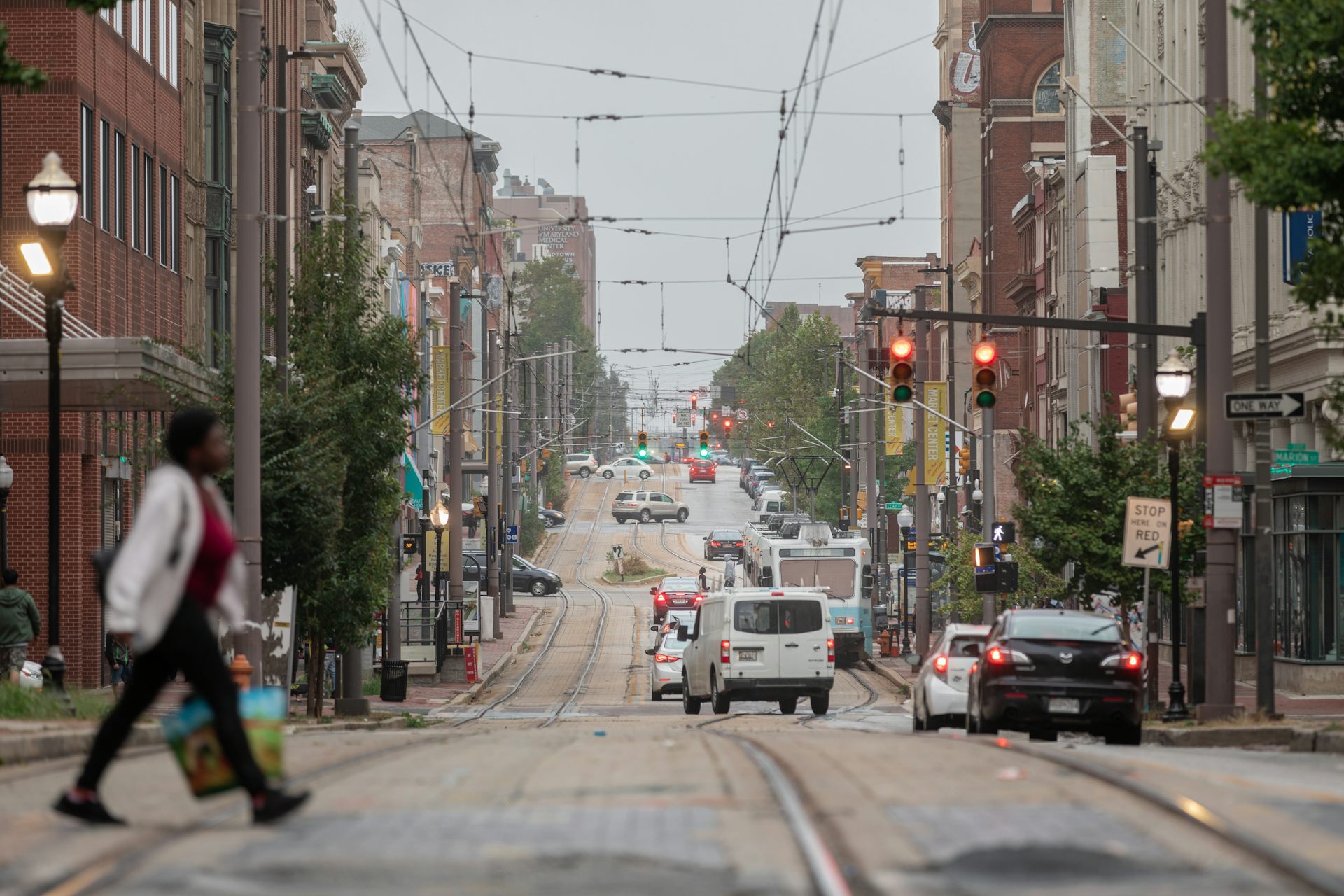 An American street with traffic lights and a woman crossing the road.