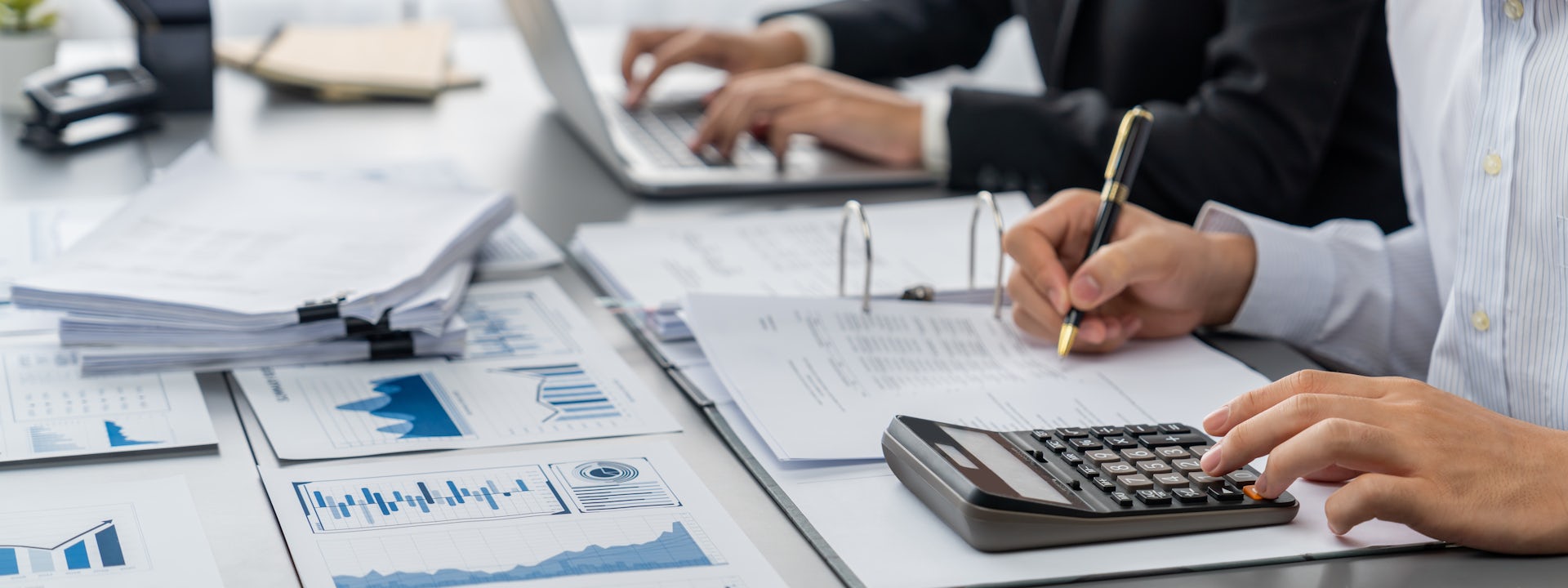 Auditor and accountant team work at table with calculators, financial documents