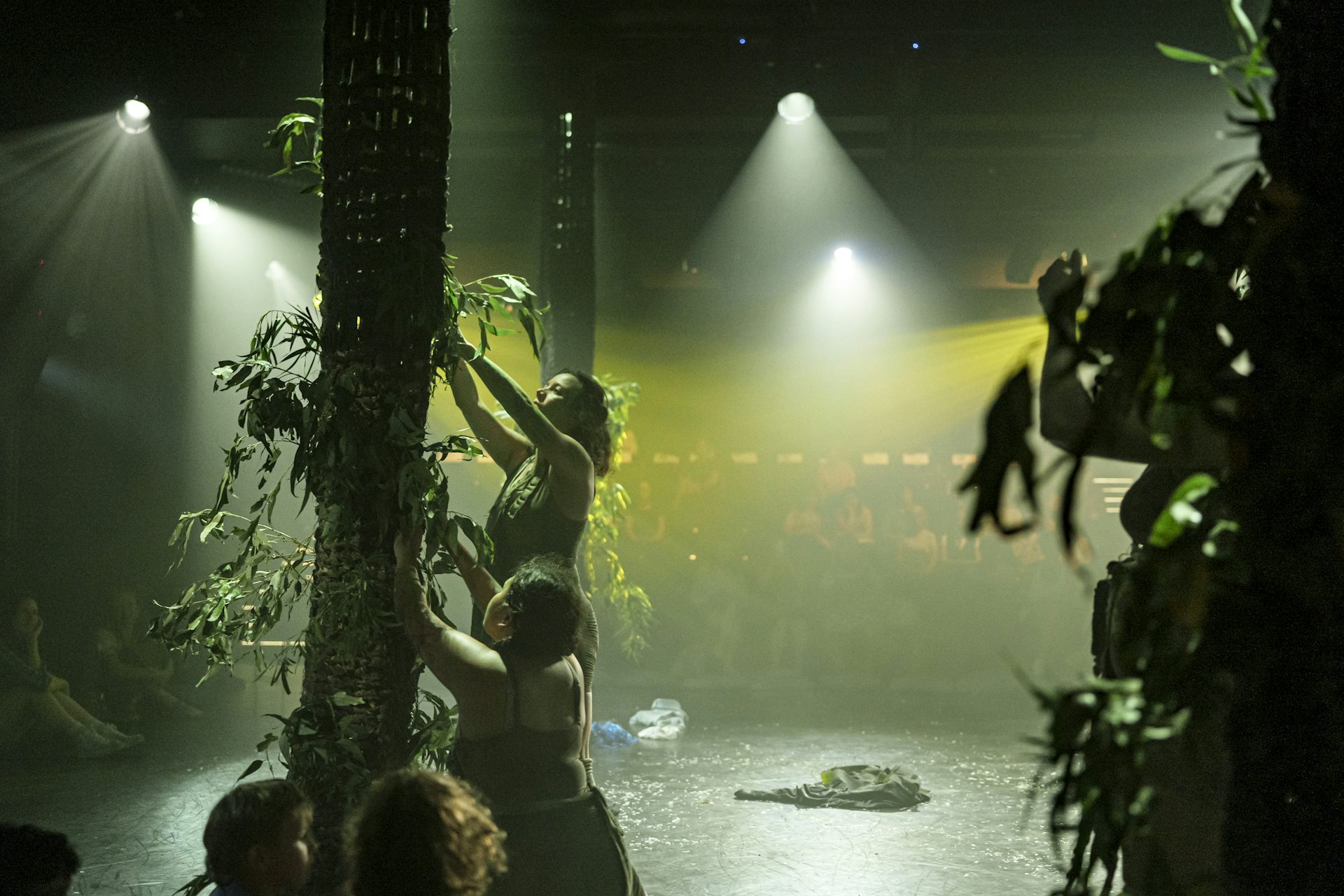 Women place gum leaves into a wooden structure.