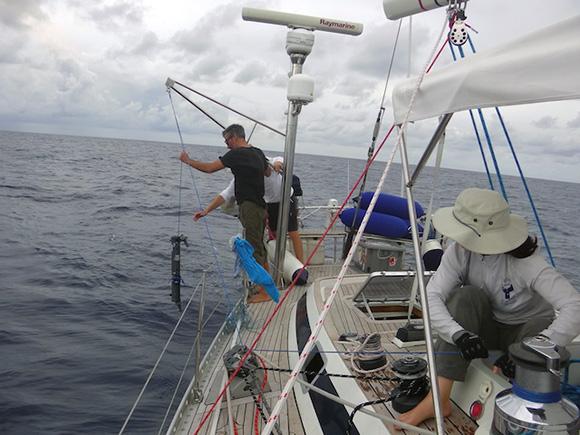Professors Grzymski and Cullen deploy a niskin bottle from the stern of S/Y Indigo V as crew Ruth McCance operates the winch