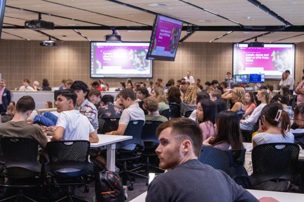 Students sit in a classroom and watch a presentation