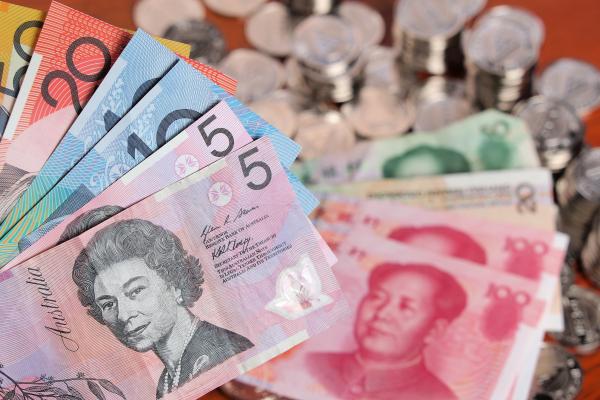 Assortment of Australian Dollar bank notes on front of a pile of Chinese bank notes