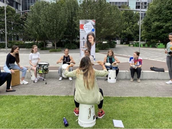 A group of women playing drums on campus