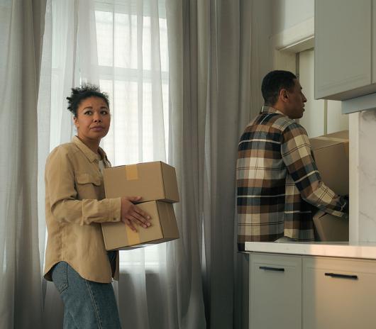 Stock picture of a man and a woman leaving a house carrying packing boxes. Picture: Yuliia/Adobe Stock