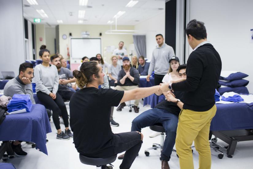 Physiotherapist demonstrating treatment on patient whilst students watch