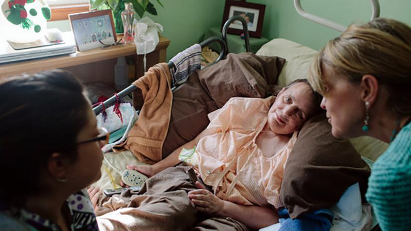 Nurse speaks to palliative care patient and family member in hospital