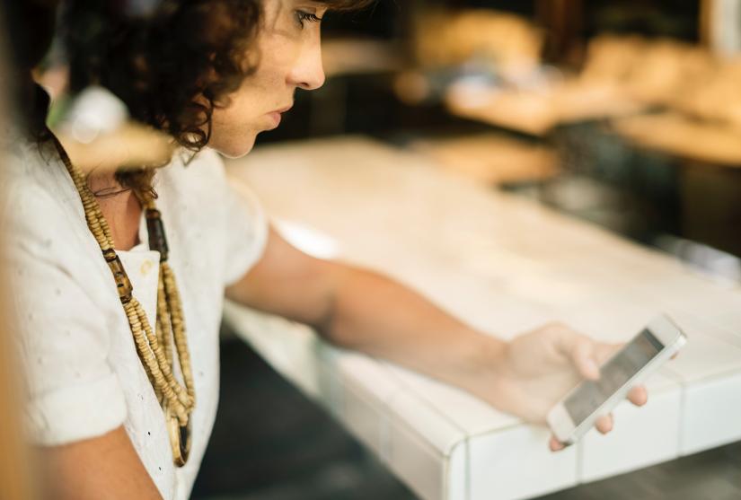 A woman looks pensively at her smart phone