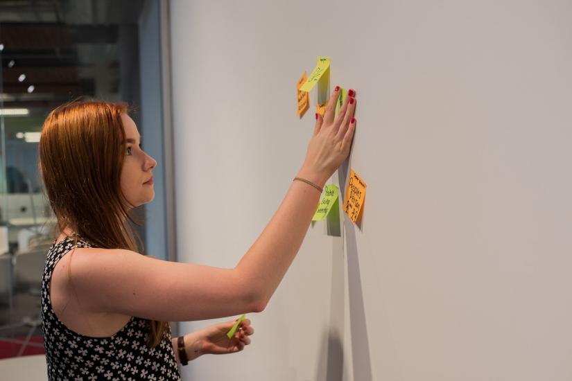 Student mapping a process on the wall using post it notes
