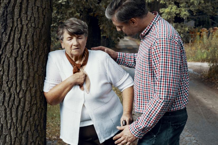 Elderly woman struggling to breathe, man by her side