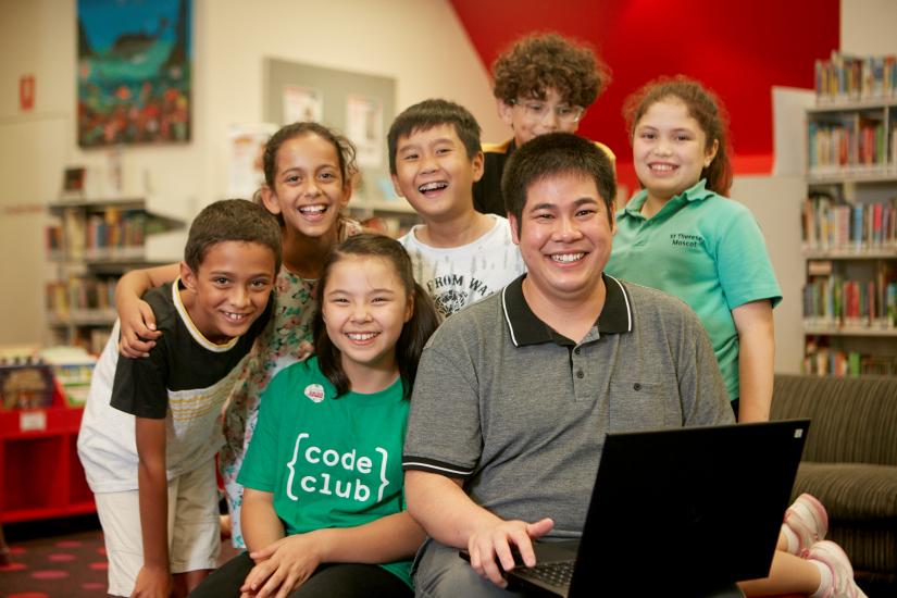 Chau Au posing with students from his Code Club program.