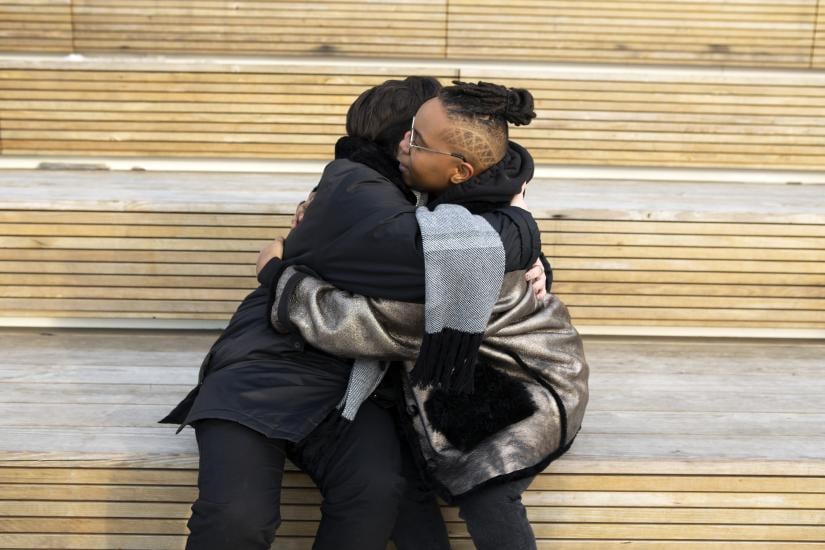 Two people hugging on a bench