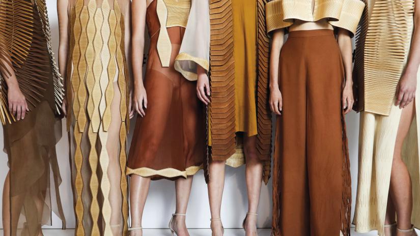Close-up of fashion outfits worn by six models. The clothes are made from silk and wool in warm brown and cream tones. All include edgings or overlays made of laser-cut wood.