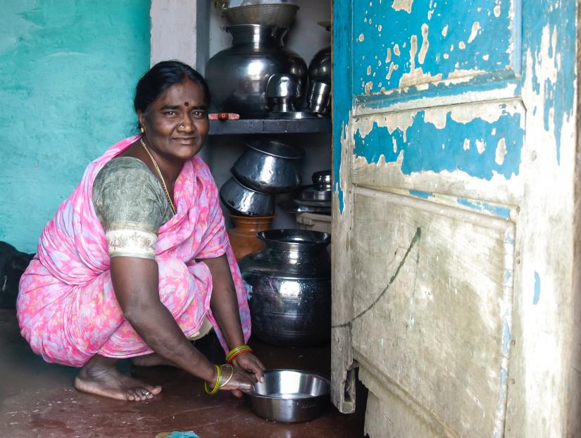 Woman squatting on the floor with water in a metal bowl.