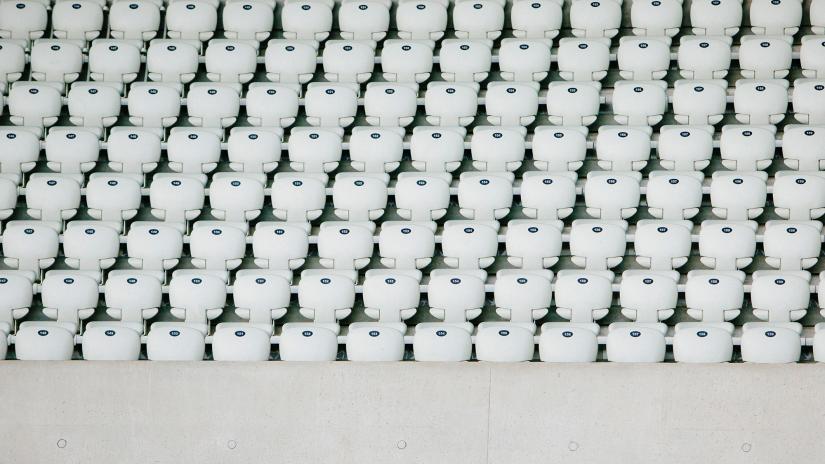 Hundreds of empty white seats in a sporting stadium