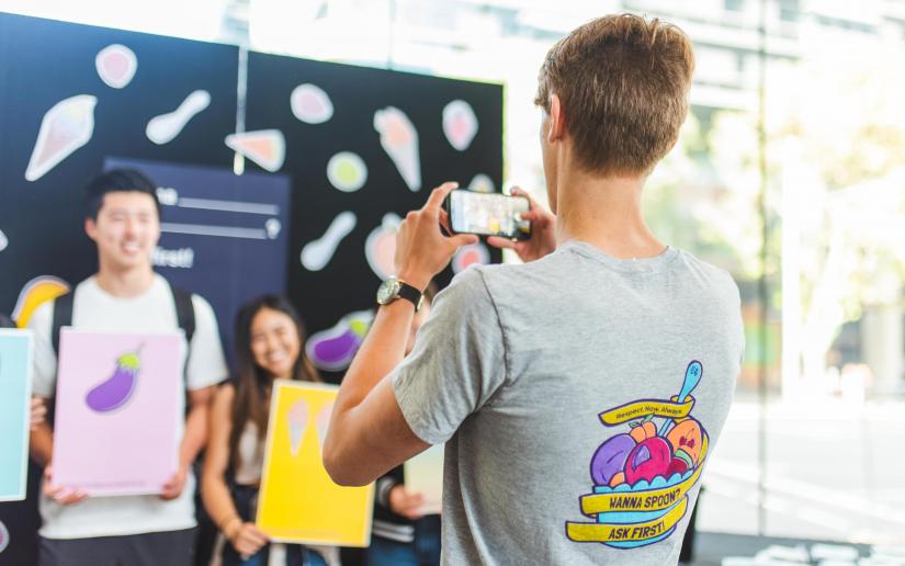 A student takes a photo of other students brandishing Respect.Now.Always gear.