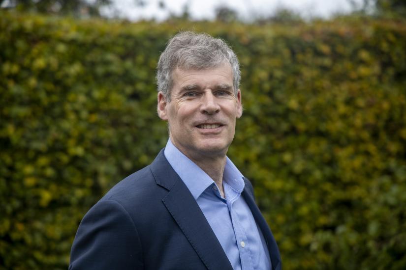 A man dressed in a suit looks at the camera