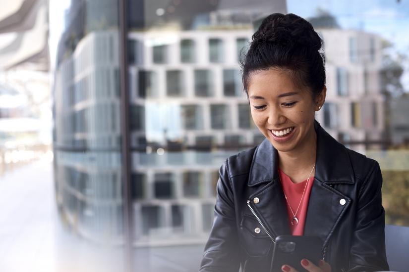 Female persona wearing black leather jacket and browsing her mobile on UTS campus