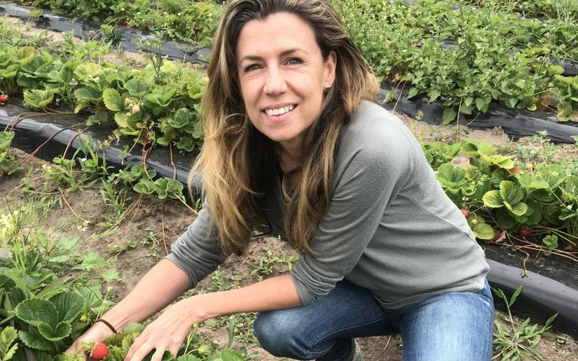 Karen O'Connell posing for a photo in a strawberry patch.