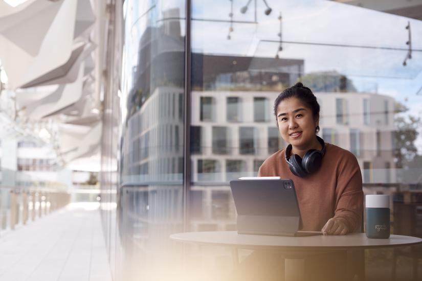 UTS female student wearing headphones studying on campus - building reflection background