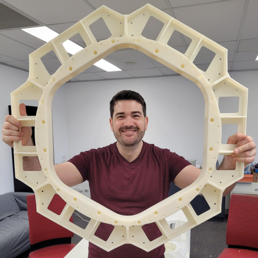 Clyde holding a full-scale prototype of the top plate of the Space Machines Company’s spacecraft upper bay