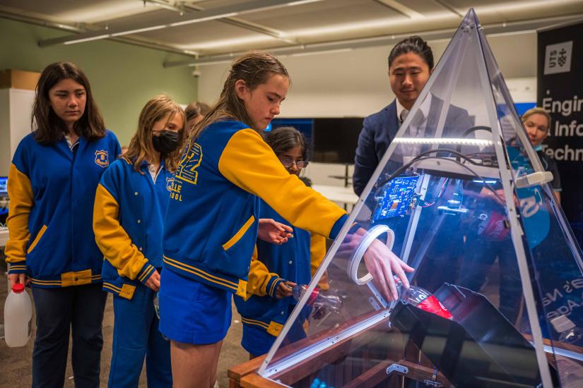 Students feed recycling into the Smart Bin as Dr Xu Wang looks on.