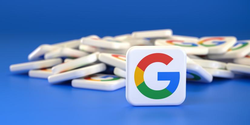 Logos of the company Google / Alphabet on a heap. One tile standing upright in front.