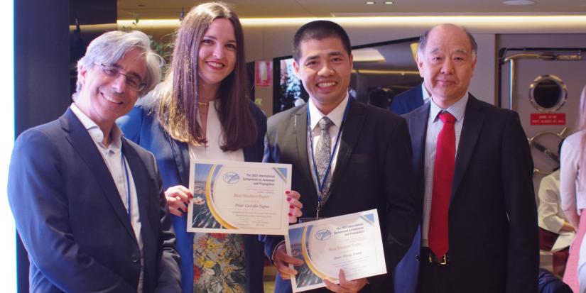 Two award winners being presented their certificates by two Professors