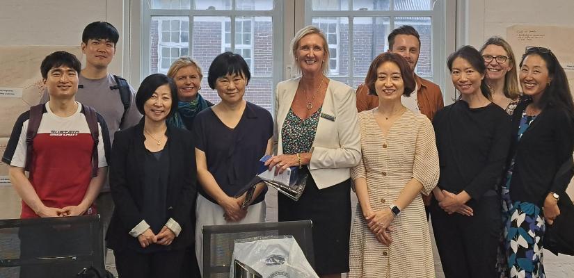 Group photo shot of several people inside a room, against a window.