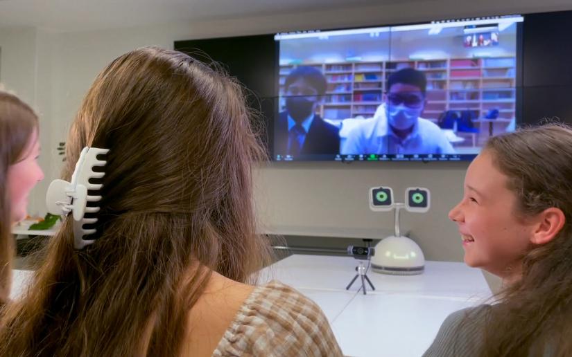 A group of children speak with students via Zoom with Haru the Social Robot facilitating the conversation.