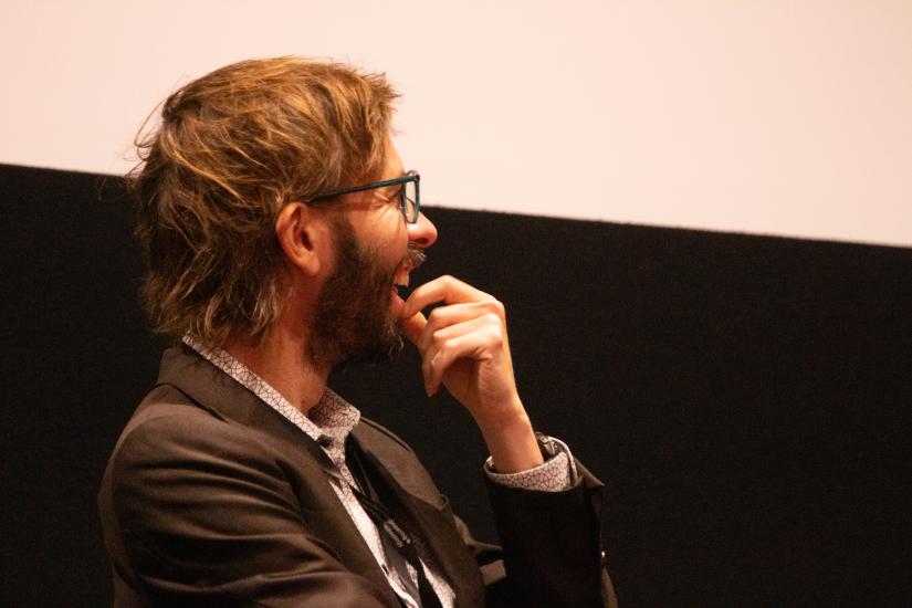 A man laughs at a conversation on stage