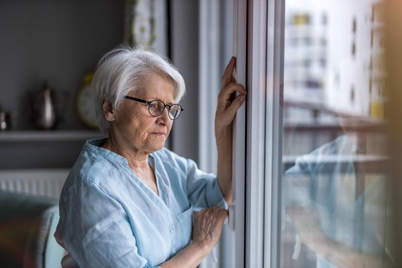 Senior woman looking out of window at home