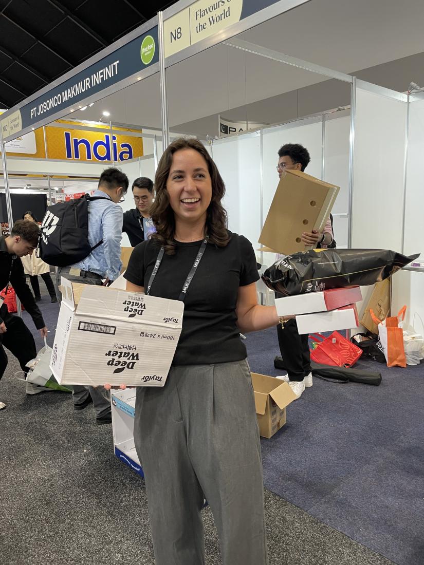 Britney stands holding boxes and bags, smiling while looking off camera