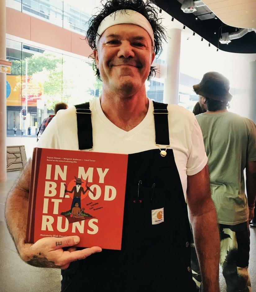 Dujuan Hoosan holds his book and smiles at the camera