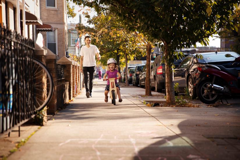 Child rides a bike down a city path