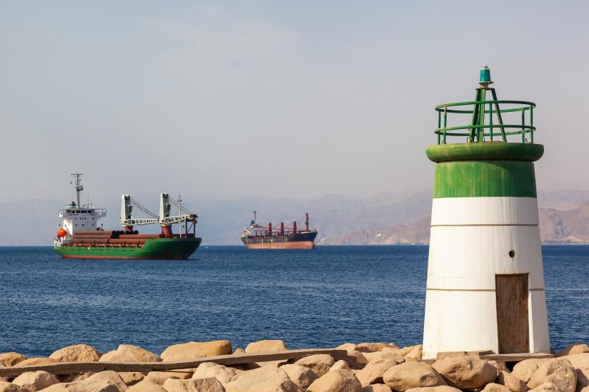 Small lighthouse on the coast of Aqaba, Jordan, with cargo ships in the background.
