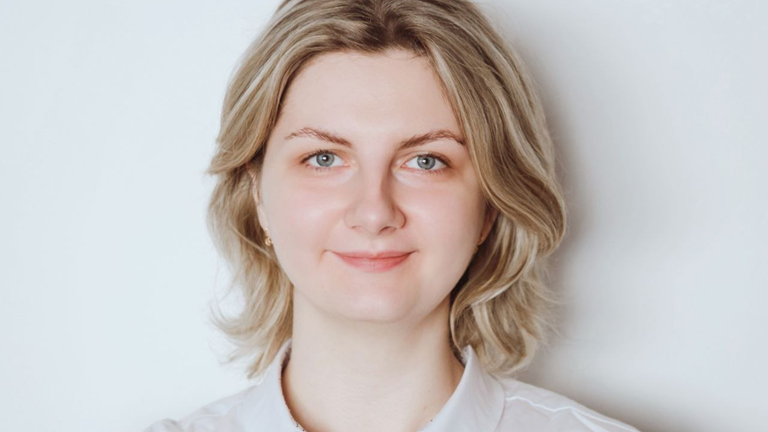 Daryna smiles at the camera in front a white background