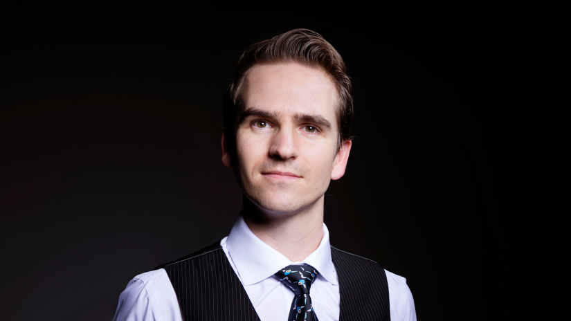Well-groomed young man with dark hair in business attire looking at camera