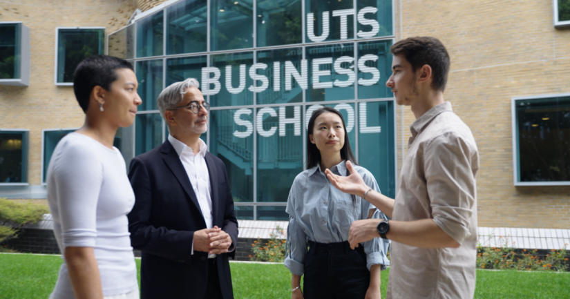 Three students and an academic standing in front of the UTS Business School