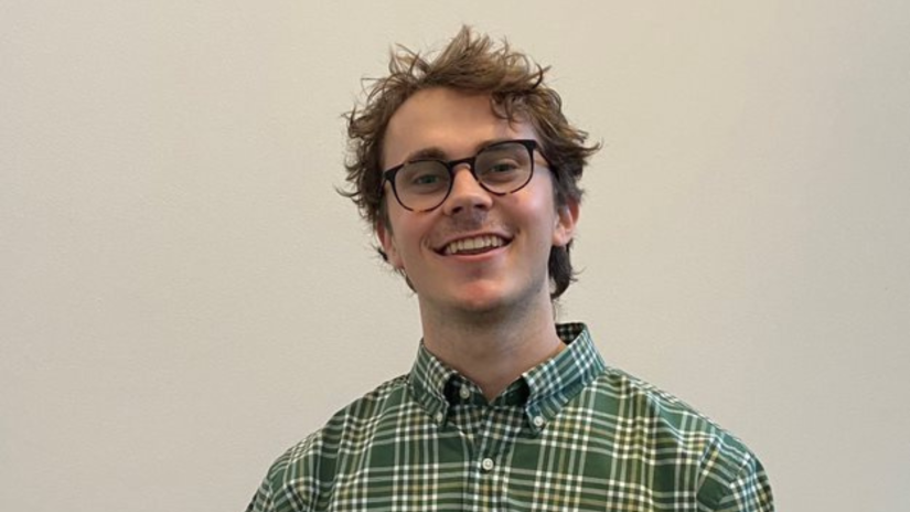Close-up headshot of Daniel in checkered shirt and wearing reading glasses