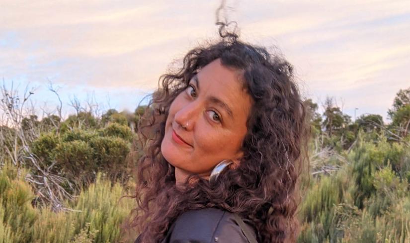 A woman stands in the Australian landscape, looking at the camera